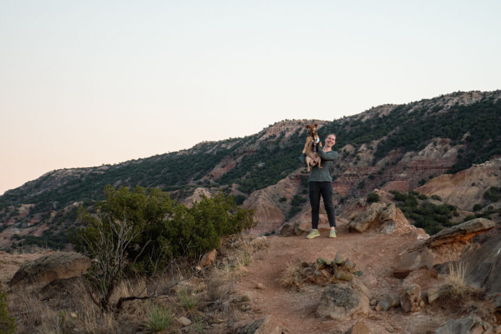 woman holding dog on hiking trail