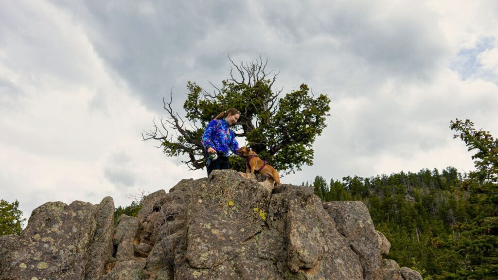 Woman and dog on top of boulder on Kruger Rock Trail Estes Park CO