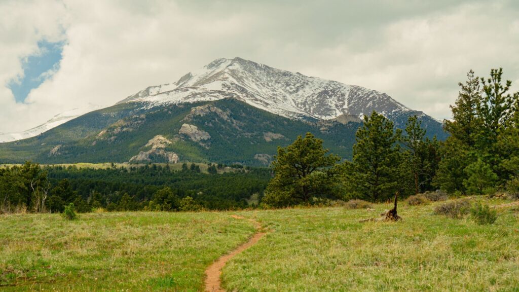 snowy mountain with hiking trail leading towards it