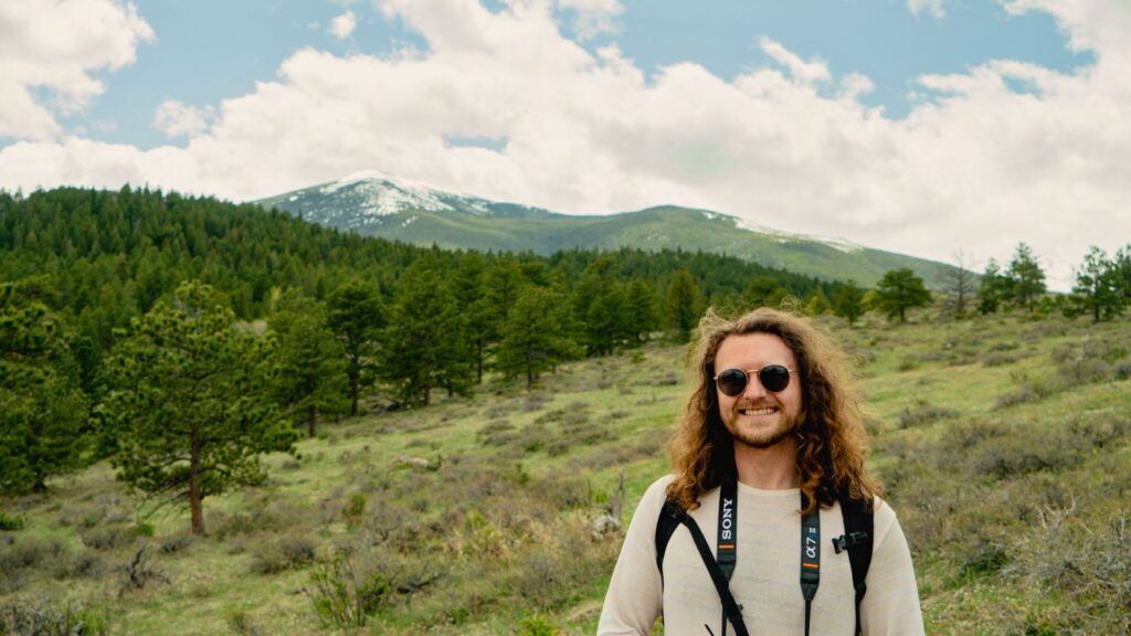 man smiling in front of mountains and pine trees in Colorado