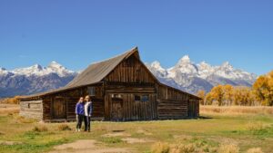 Couple standing in front of old bard in Grand Teton National Park Wyoming