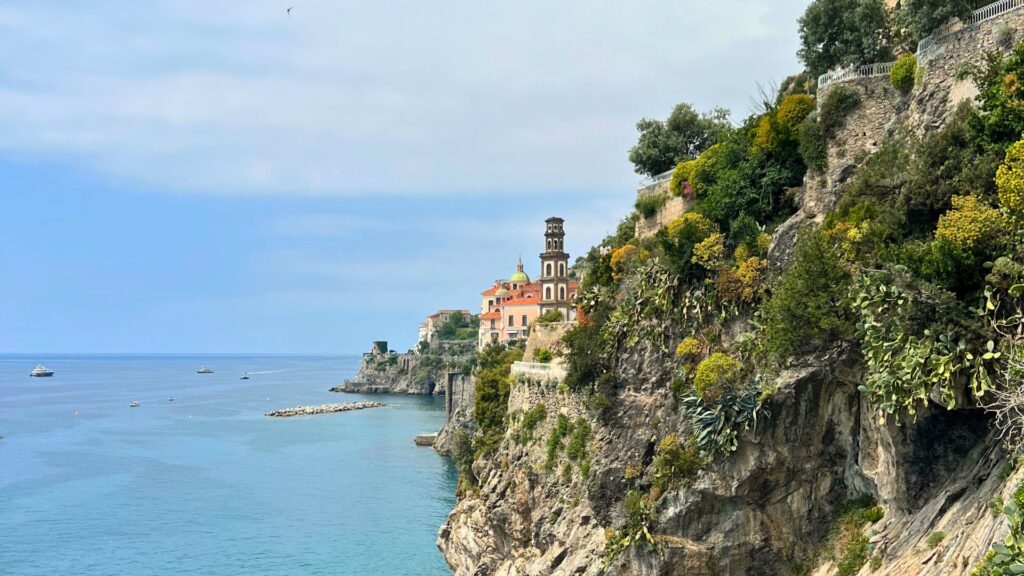 Buildings peeking out on rocky coast and ocean - How to Get From Naples to Amalfi Italy