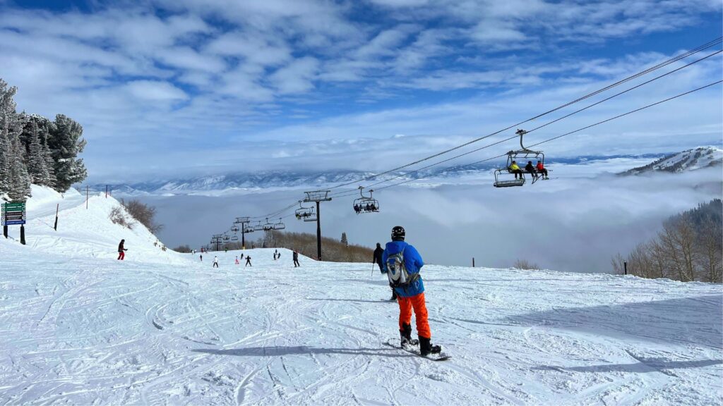 Snowboarder at top of ski run chair lift in background