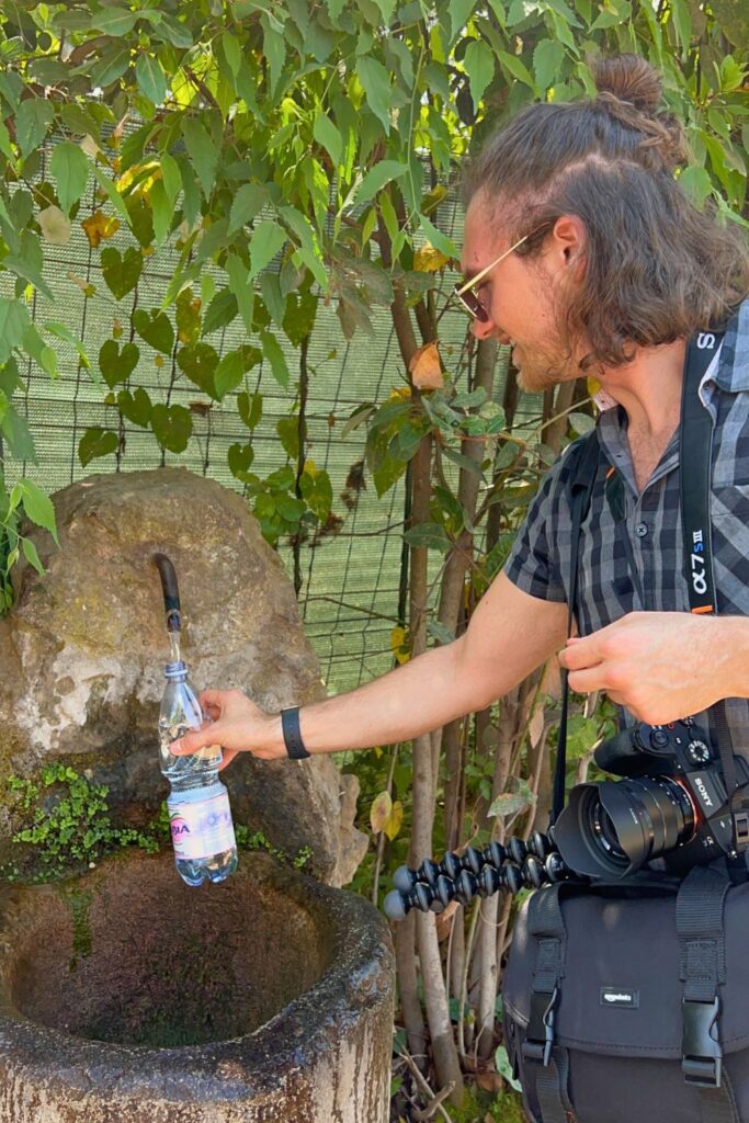 Man filling up bottle at water fountain in Rome