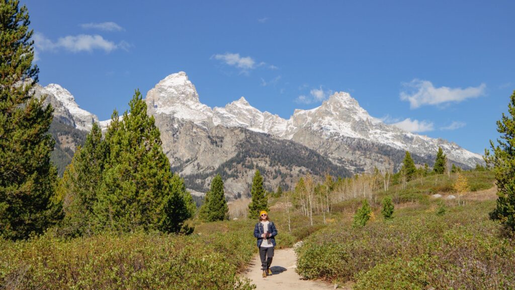 Nate hiking by snowy mountain tops in Grand Teton